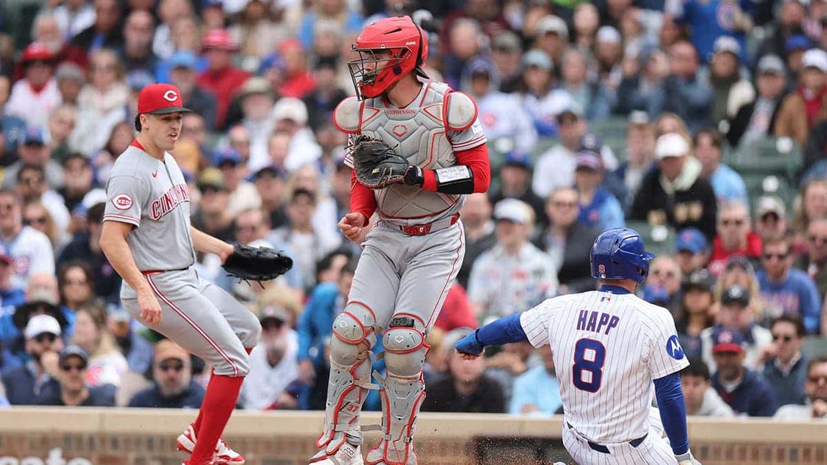 Ian Happ scoring a run past Tyler Stephenson at Wrigley Field