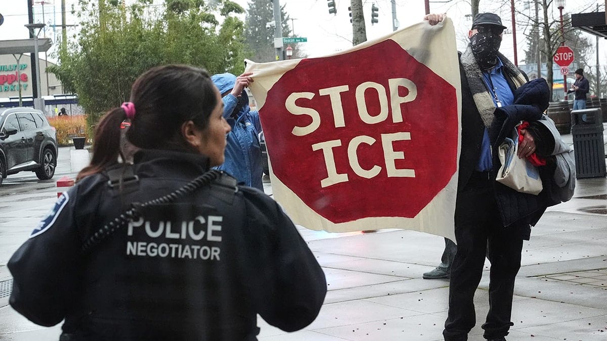 Protesters holding a Stop ICE sign during a bill-signing event in Seattle