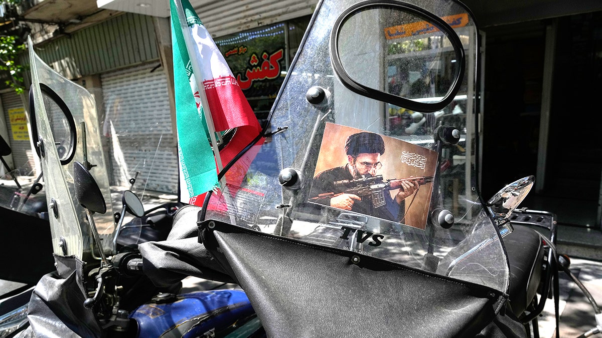 A poster of Ayatollah Mojtaba Khamenei is attached to the windshield of a motorcycle.