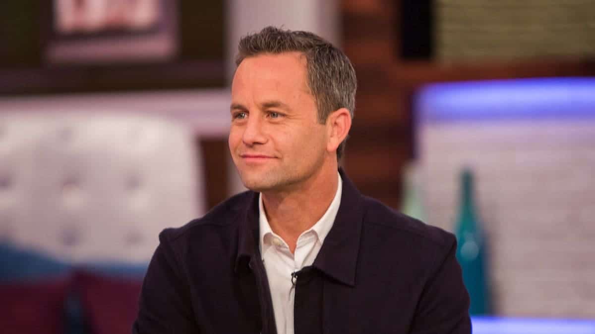 Kirk Cameron standing and smiling in a studio setting