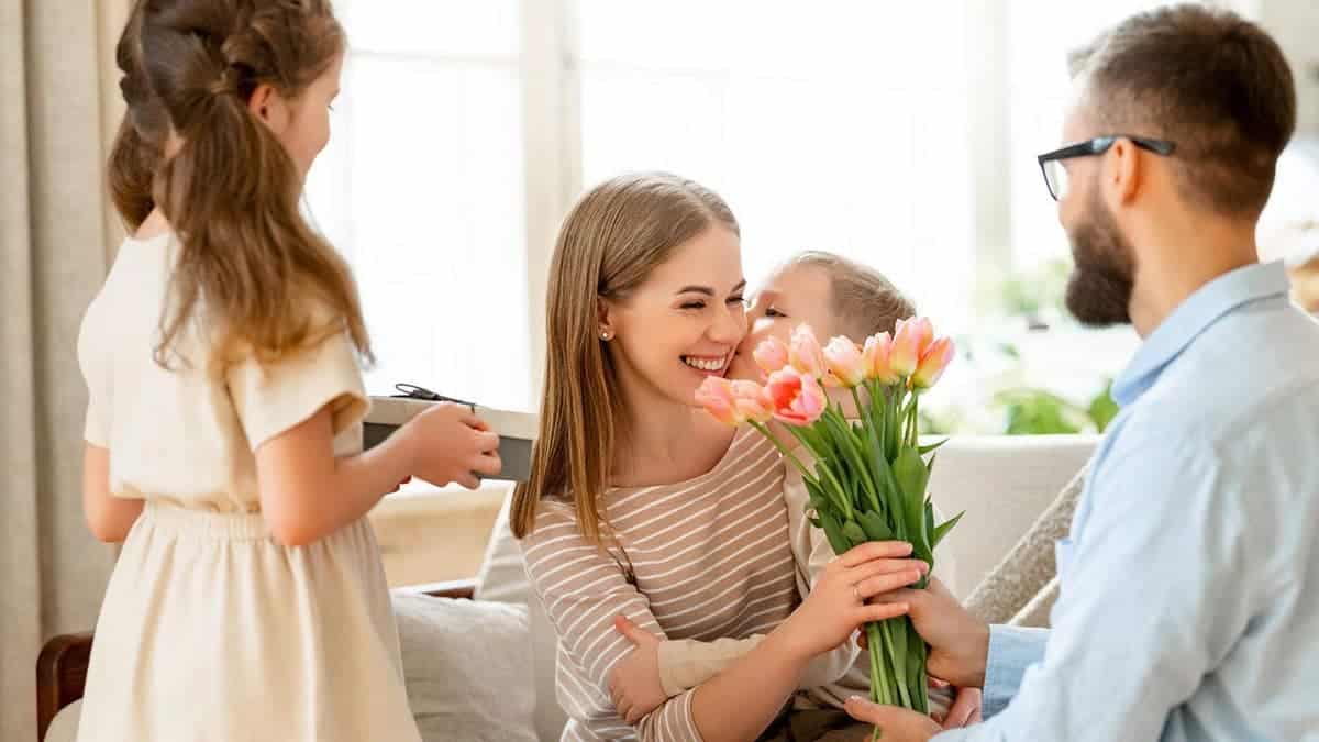 Father and children giving flowers to mother celebrating Mother's Day