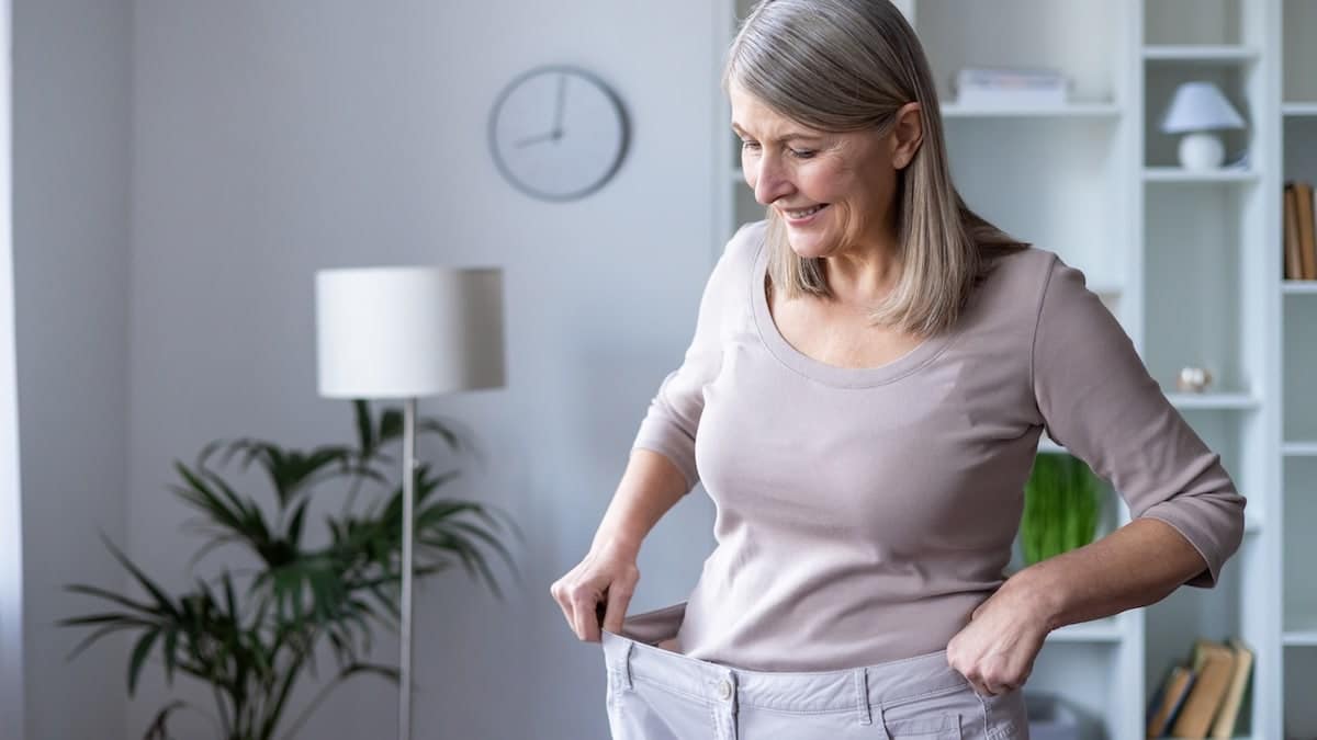 Happy senior woman wearing oversized pants standing in a modern room