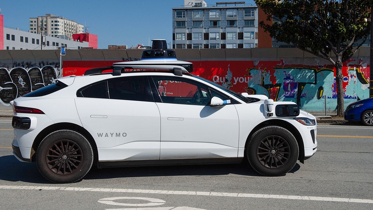 A Waymo robotaxi driving down the street.