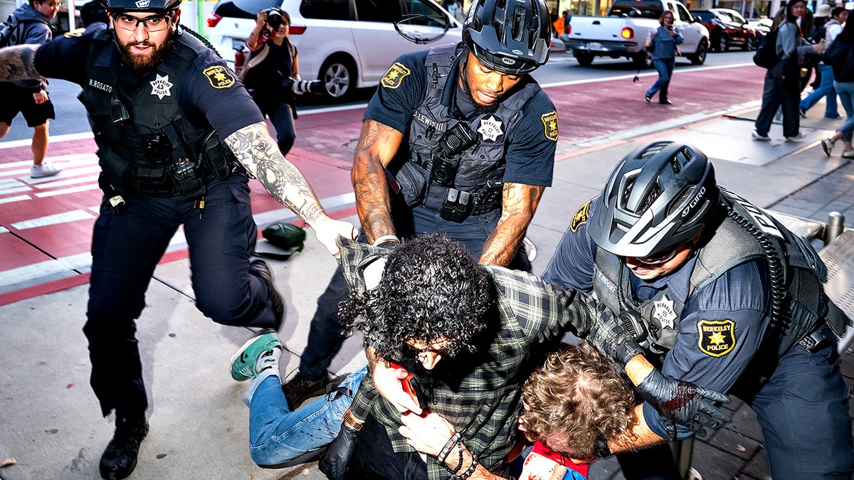 Police officers separating two men outside a Turning Point USA event at University of California Berkeley