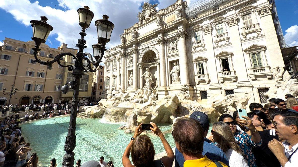 Hundreds of tourists walking and gathering around Trevi Fountain in Rome