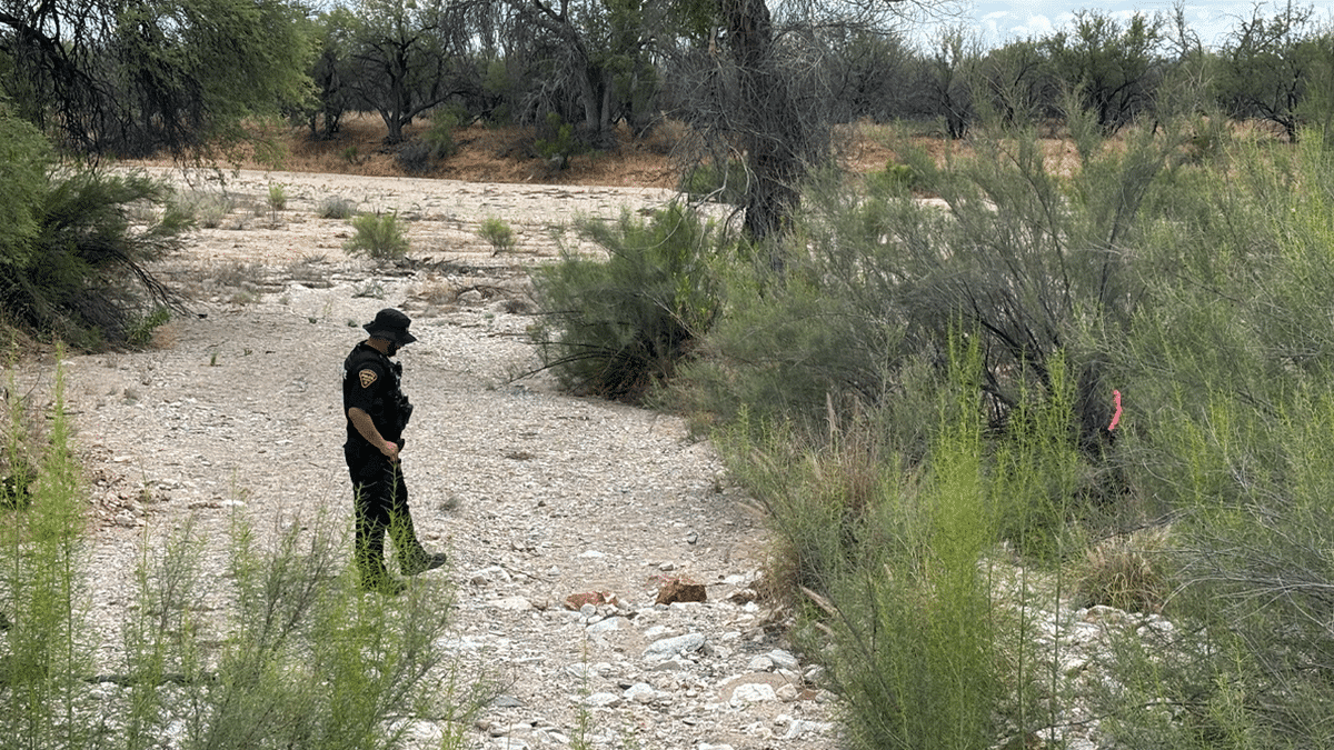A Tucson police officer stands guard near human remains in the desert