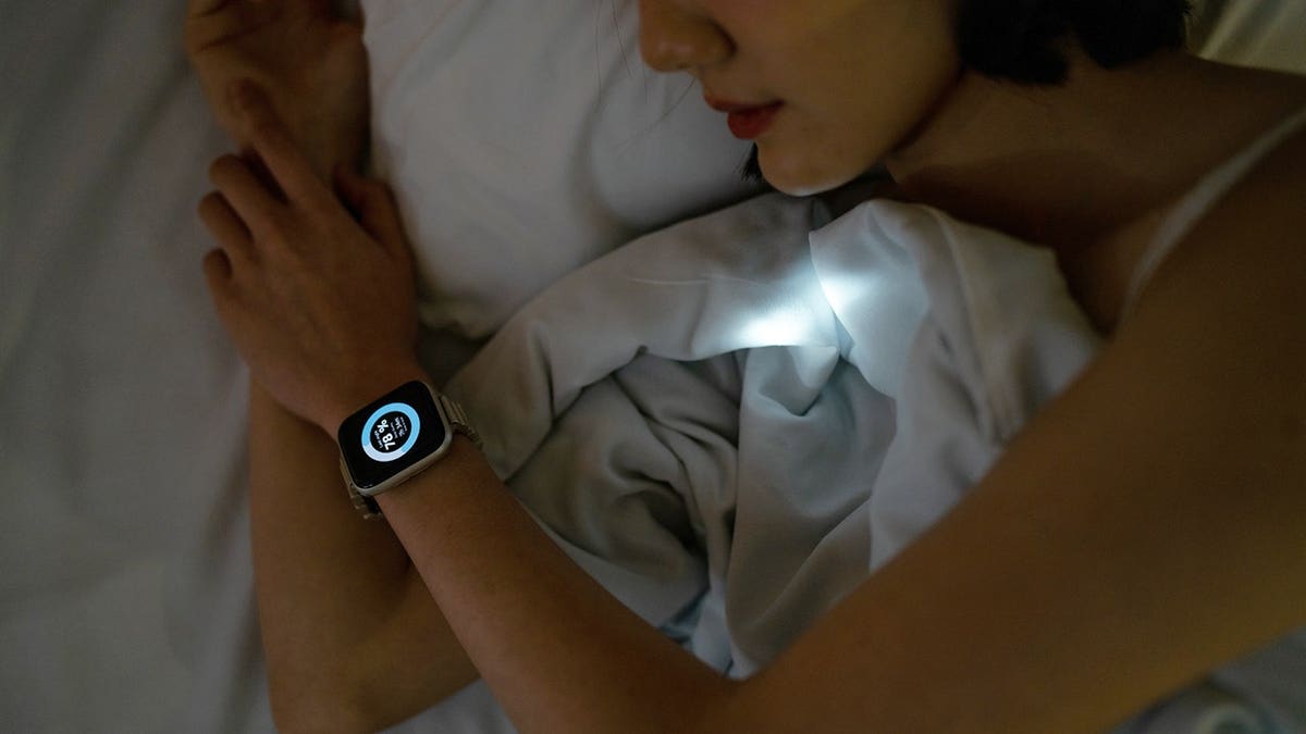 Woman sleeping peacefully in bed wearing a smartwatch.