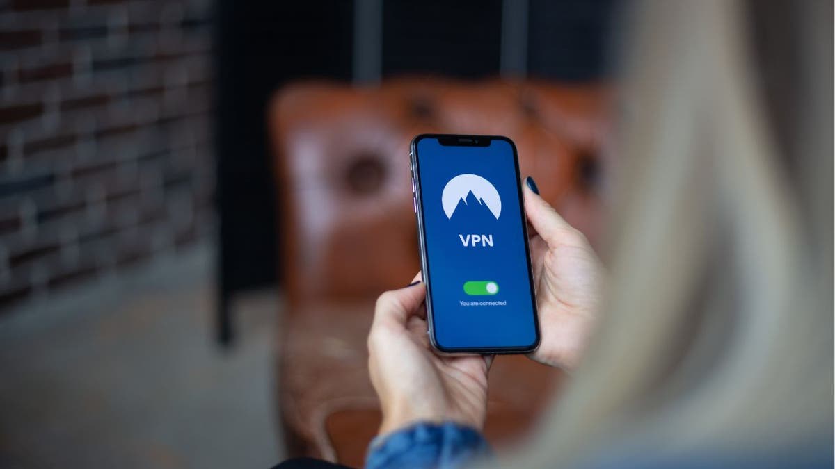 A woman holding up her phone displaying a VPN loading screen.