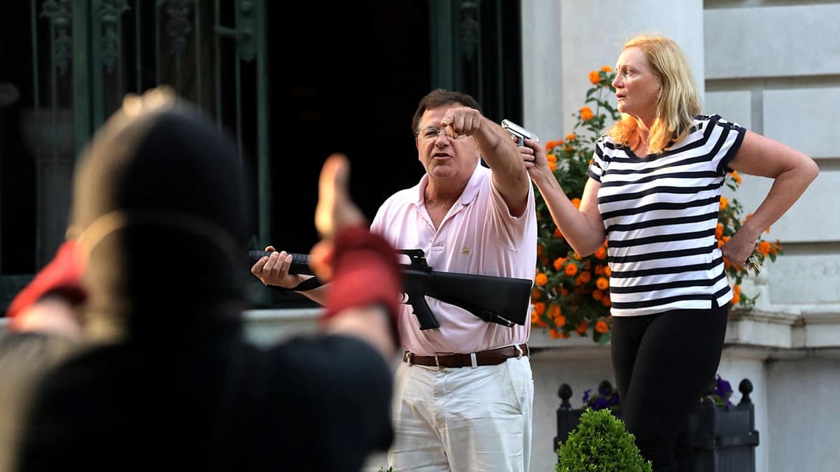 Armed homeowners Mark T. and Patricia N. McCloskey standing in front of their house holding guns