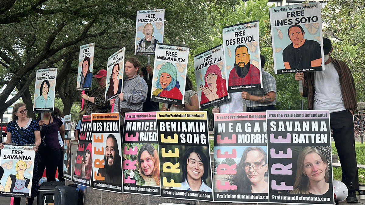 Supporters of protesters convicted over a shooting outside a Texas immigration detention center stand with signs.