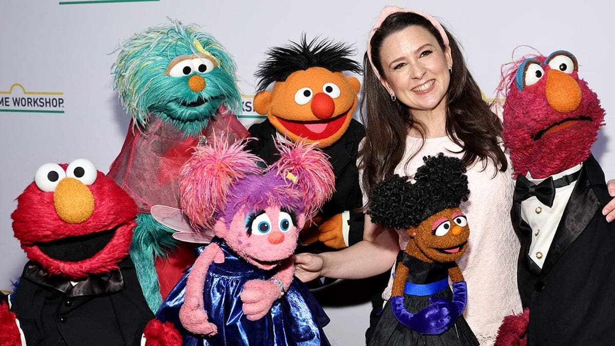 Ms. Rachel posing with Sesame Street characters at a gala event.