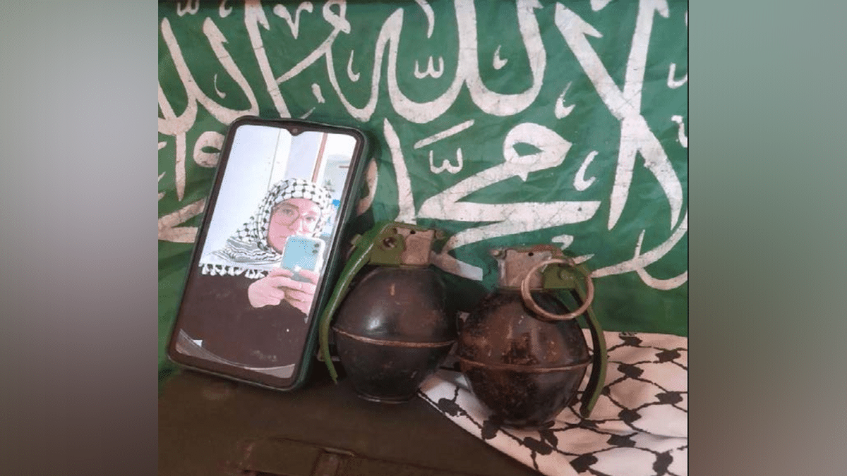 Catherine Beth Washburn pictured with two hand grenades in front of Hamas flag.