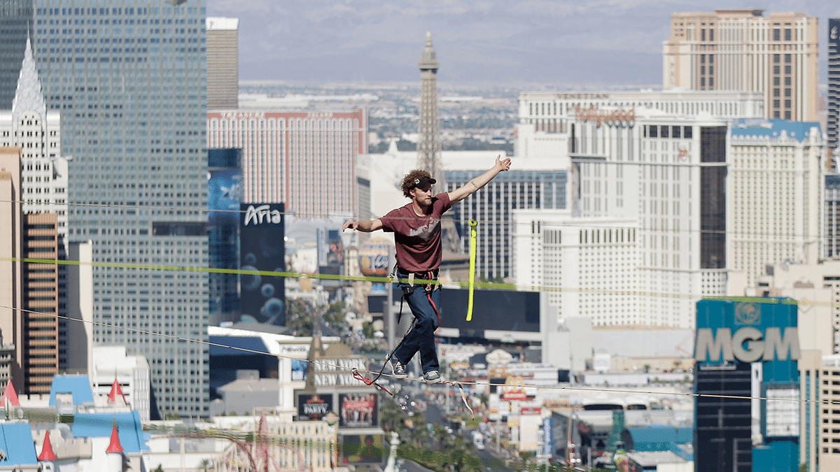 Daredevil Andy Lewis wearing a maroon T-shirt and blue pants as he walks a tightrope 480 feet above Las Vegas