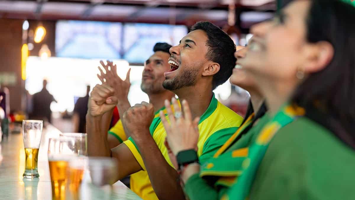Happy Brazilian soccer fans cheering and celebrating at a sports bar