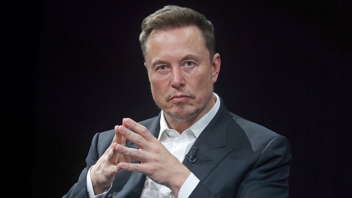 Elon Musk sitting with hands together
