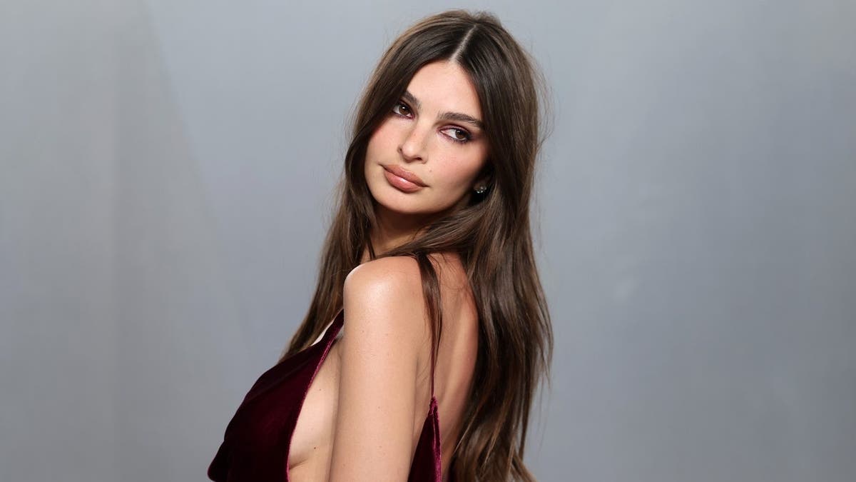 Emily Ratajkowski standing in a black dress at the Vanity Fair Oscar Party at Los Angeles County Museum of Art