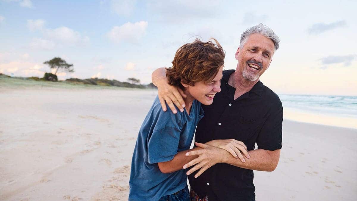 Father and teenage son playing together on a beach in Australia