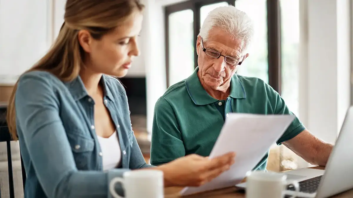 A woman and an older man look at a document together.