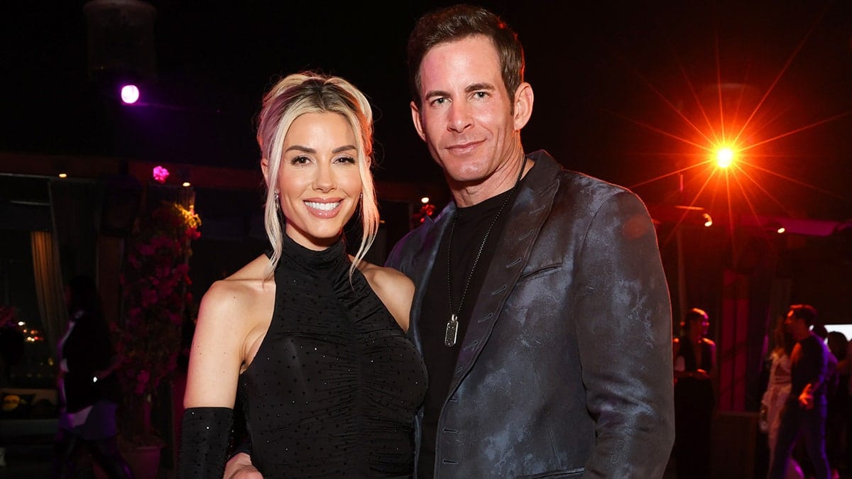 Heather Rae El Moussa and Tarek El Moussa posing together wearing matching black outfits