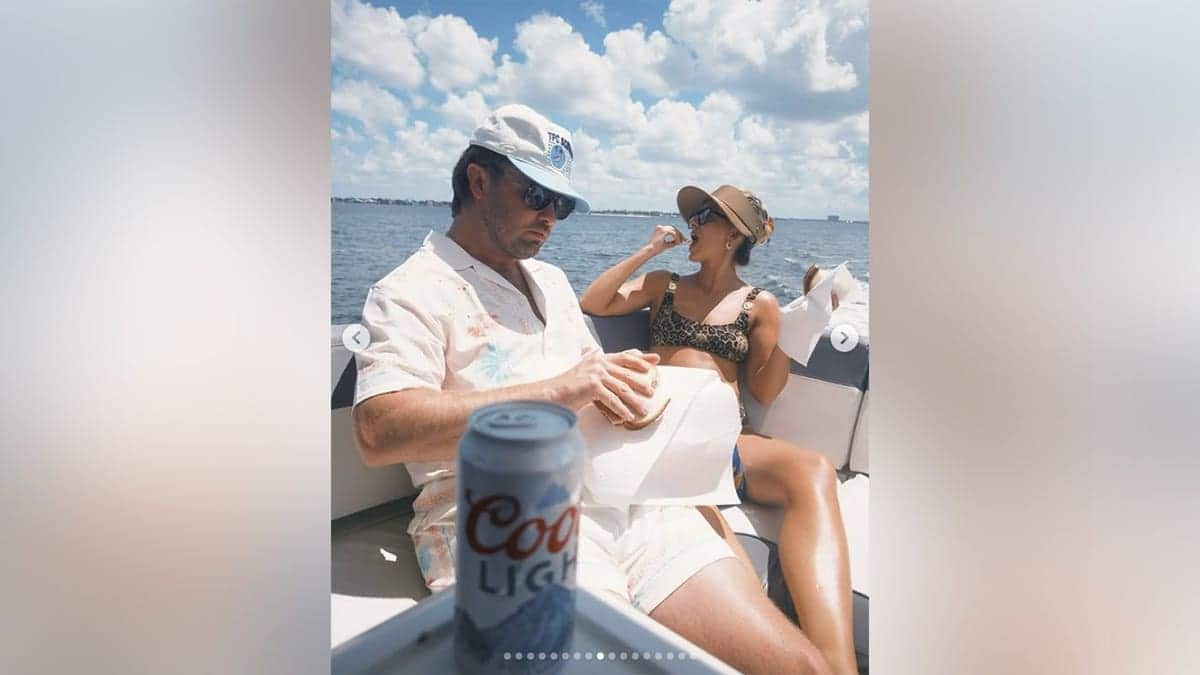 Lainey Wilson eating a sandwich on a boat while dressed in a bikini.