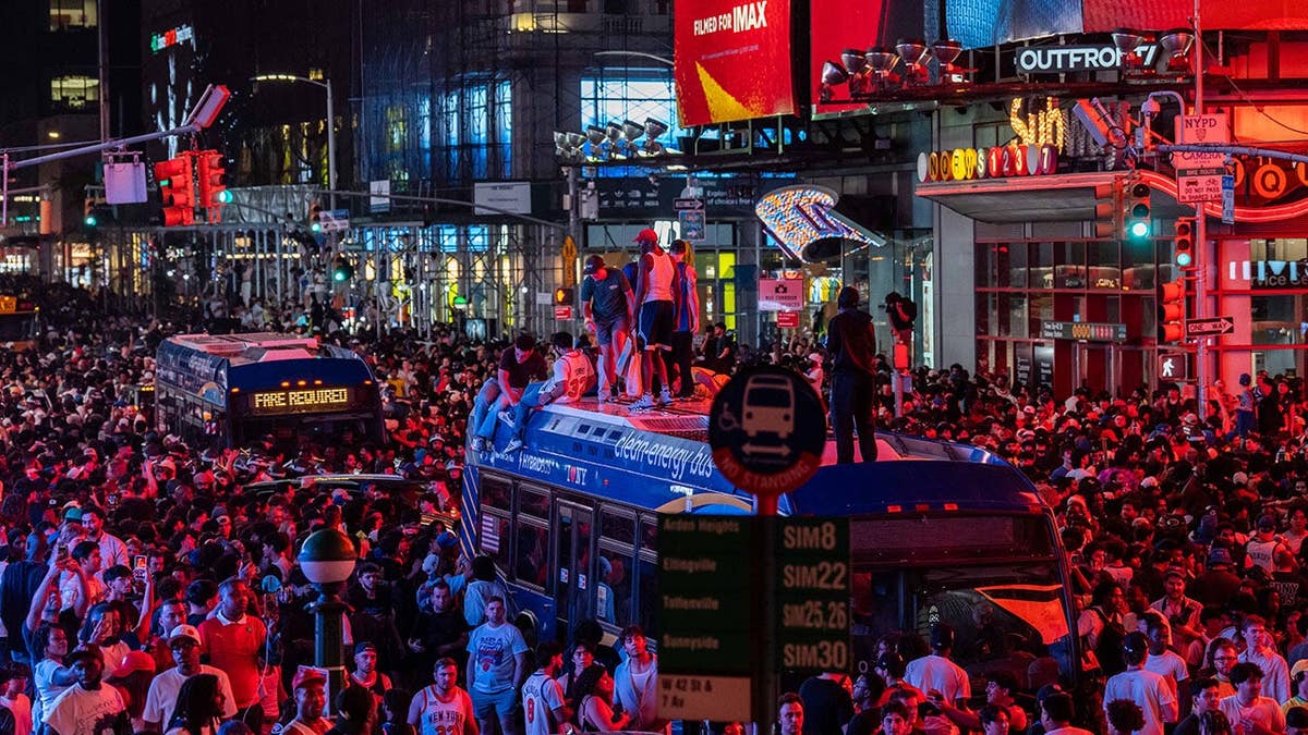 New York Knicks fans climbing on buses celebrating in Times Square New York City