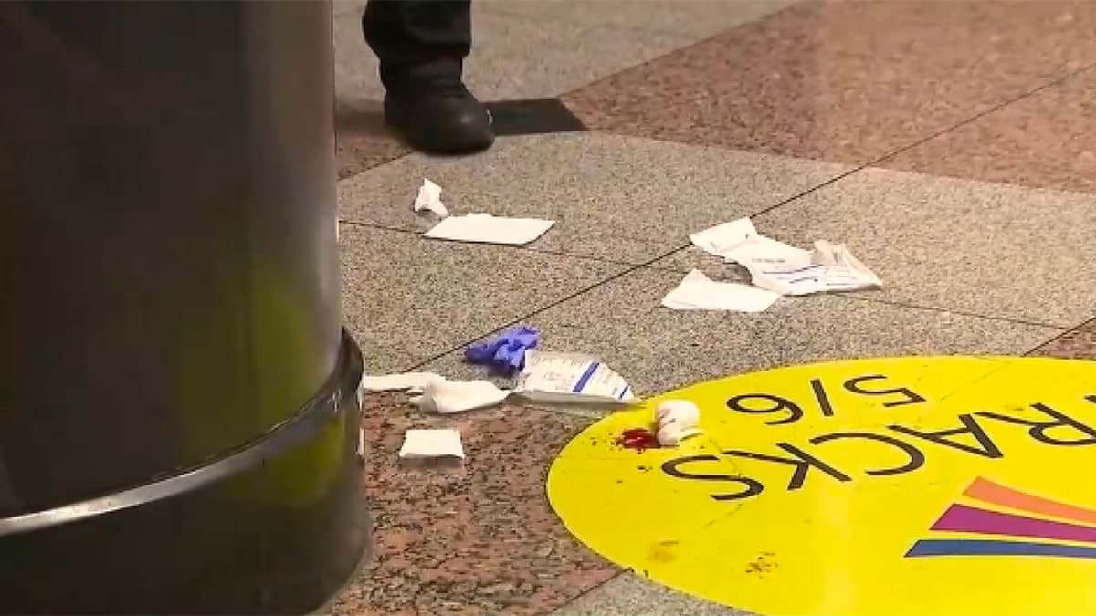 Debris, medical supplies and what appears to be blood are visible on the floor near a train platform area following a stabbing incident at New York City's Penn Station.