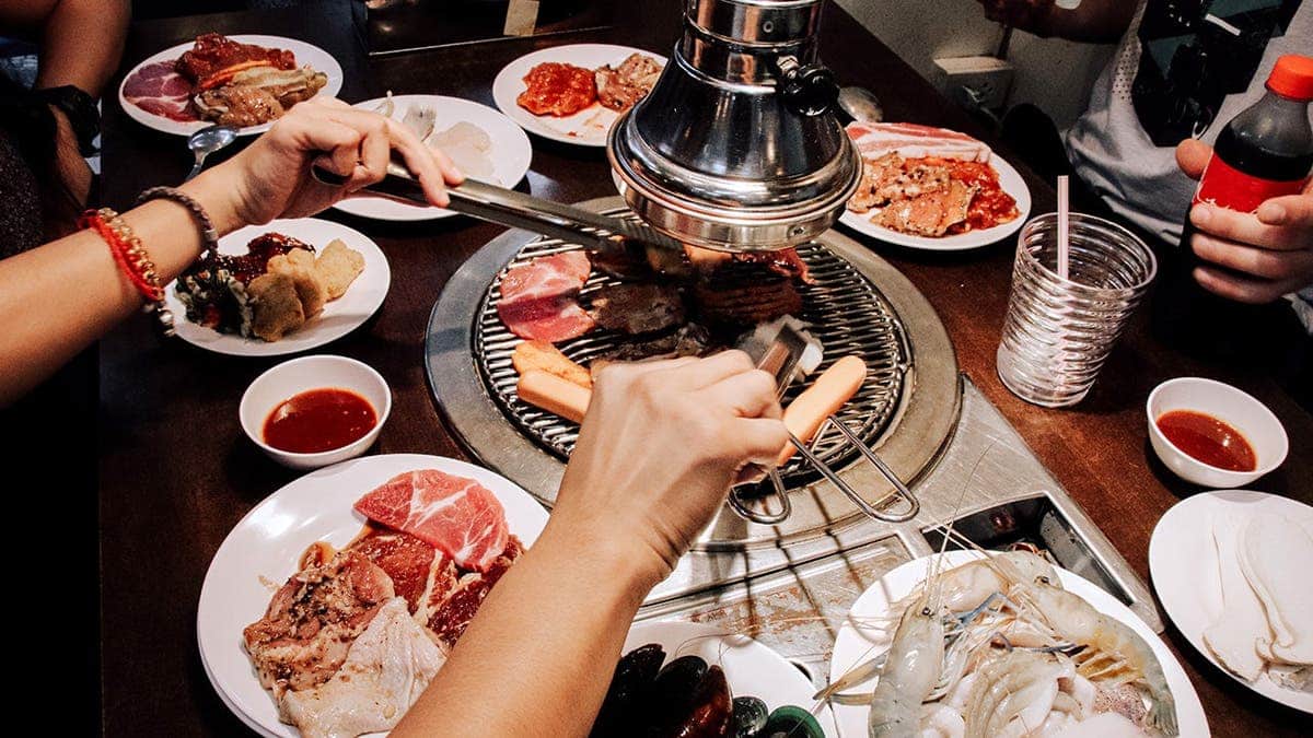 People eat a traditional Korean barbecue meal around a table together.