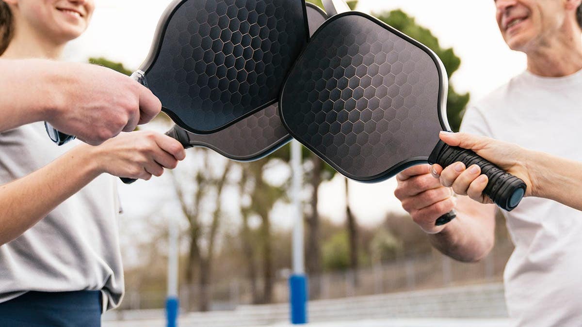 Group of pickleball players bumping paddles on an outdoor court
