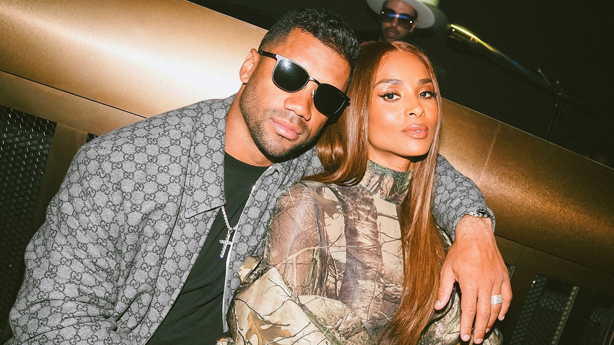 Russell Wilson and Ciara standing together at a birthday celebration event.