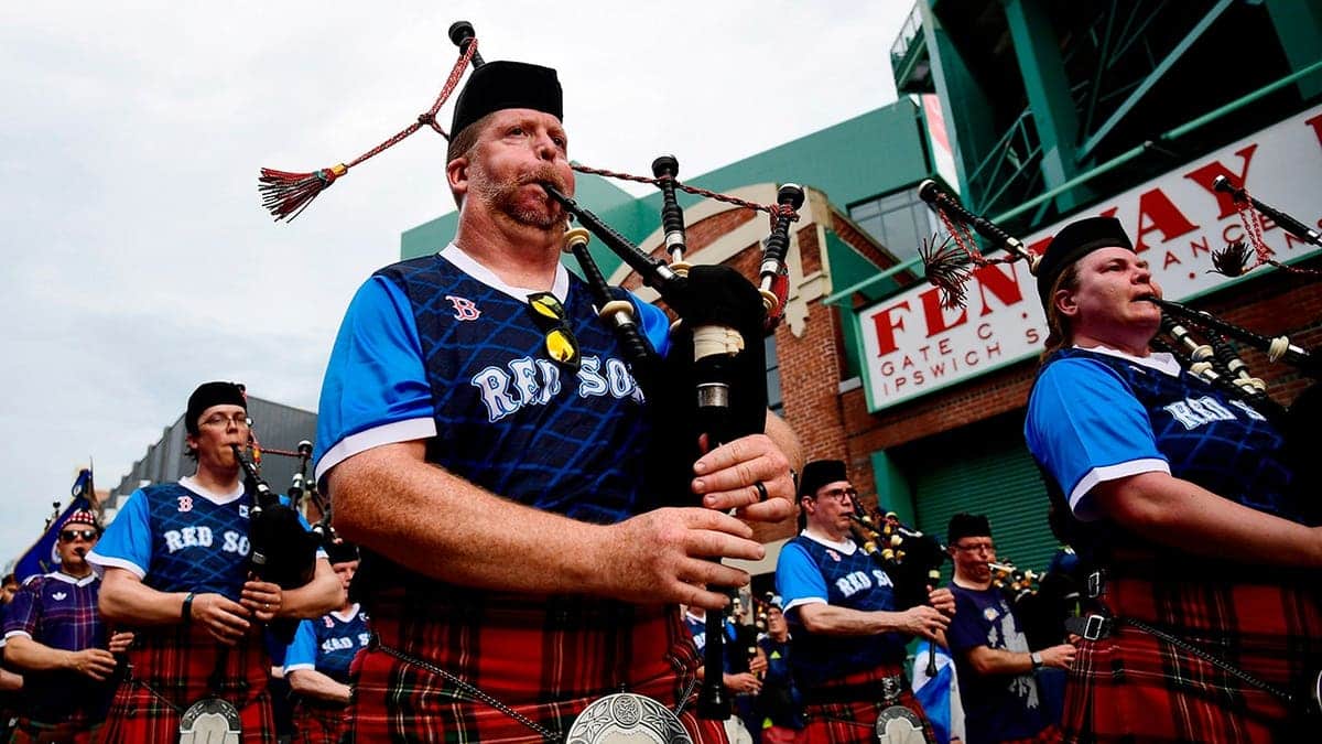 Scotland fans wearing kilts and playing bagpipes during march to Fenway Park in Massachusetts