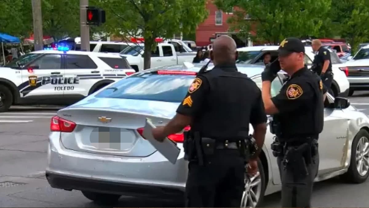 Police officers standing near vehicles at a crime scene in Toledo, Ohio