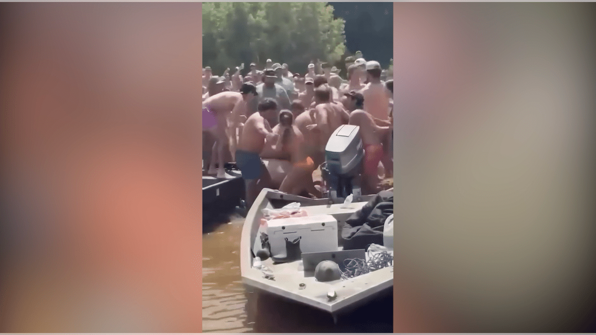People appear to grapple and exchange blows during a large fight at a South Carolina river sandbar