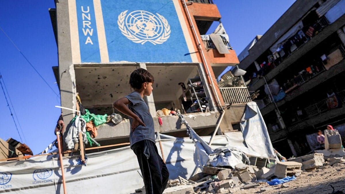 Palestinian boy walking near a building with a UNRWA sign in Gaza City