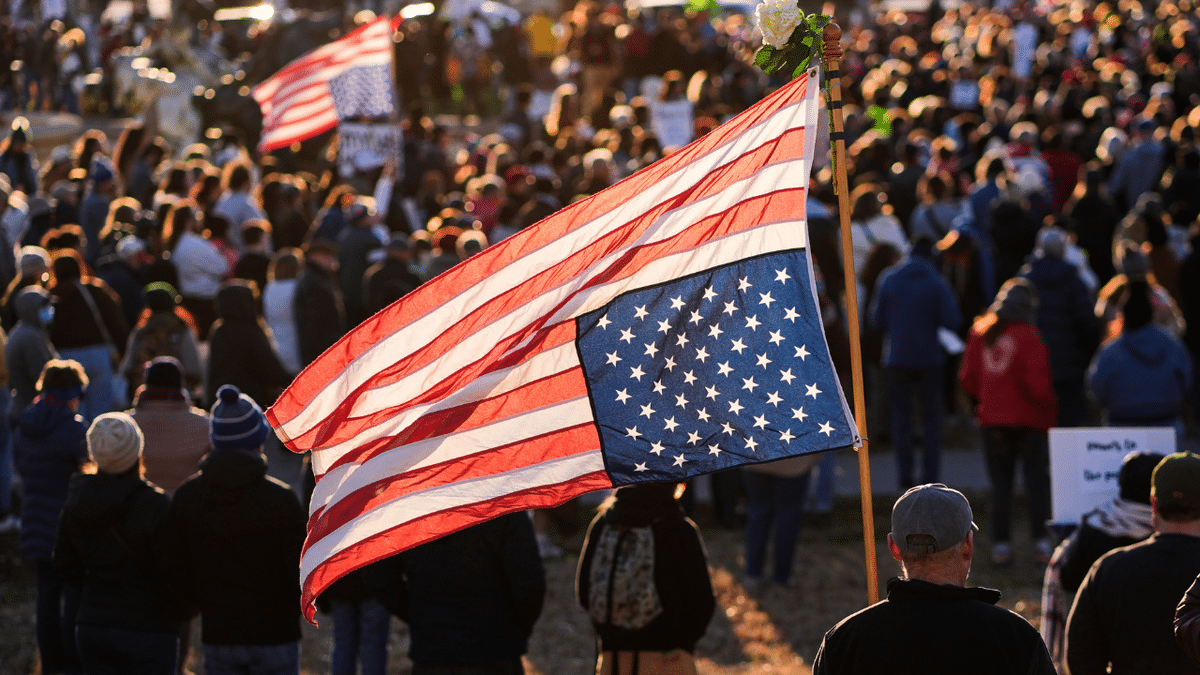 A man holds an upside down American flag.