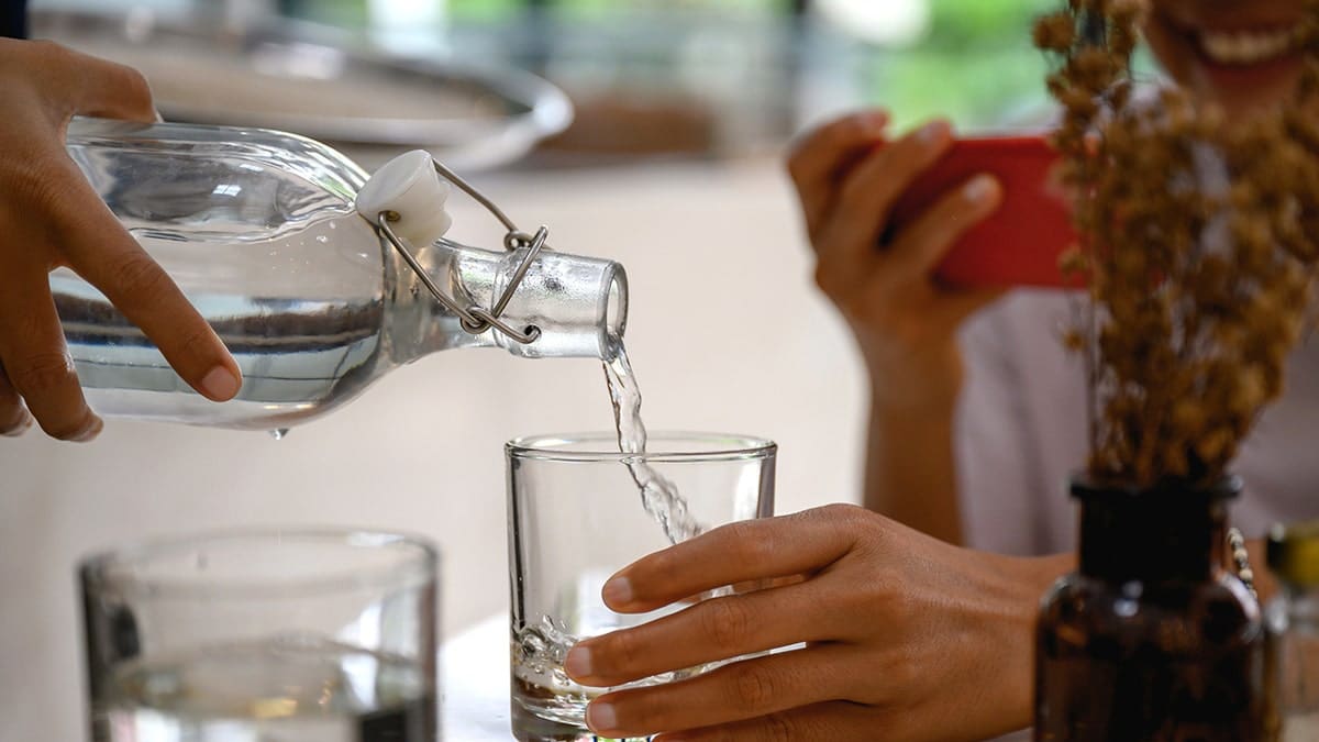 Waiter pouring fresh cold water into a drinking glass at a restaurant