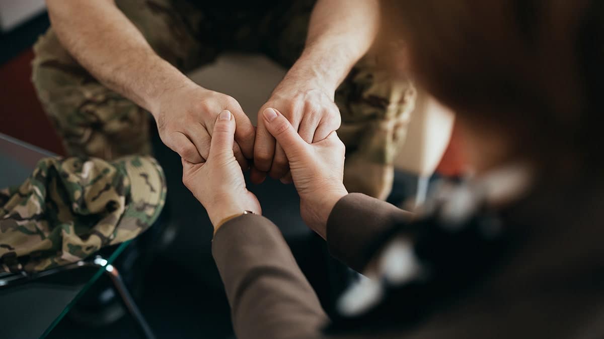 Military man holding hands with therapist during counseling session