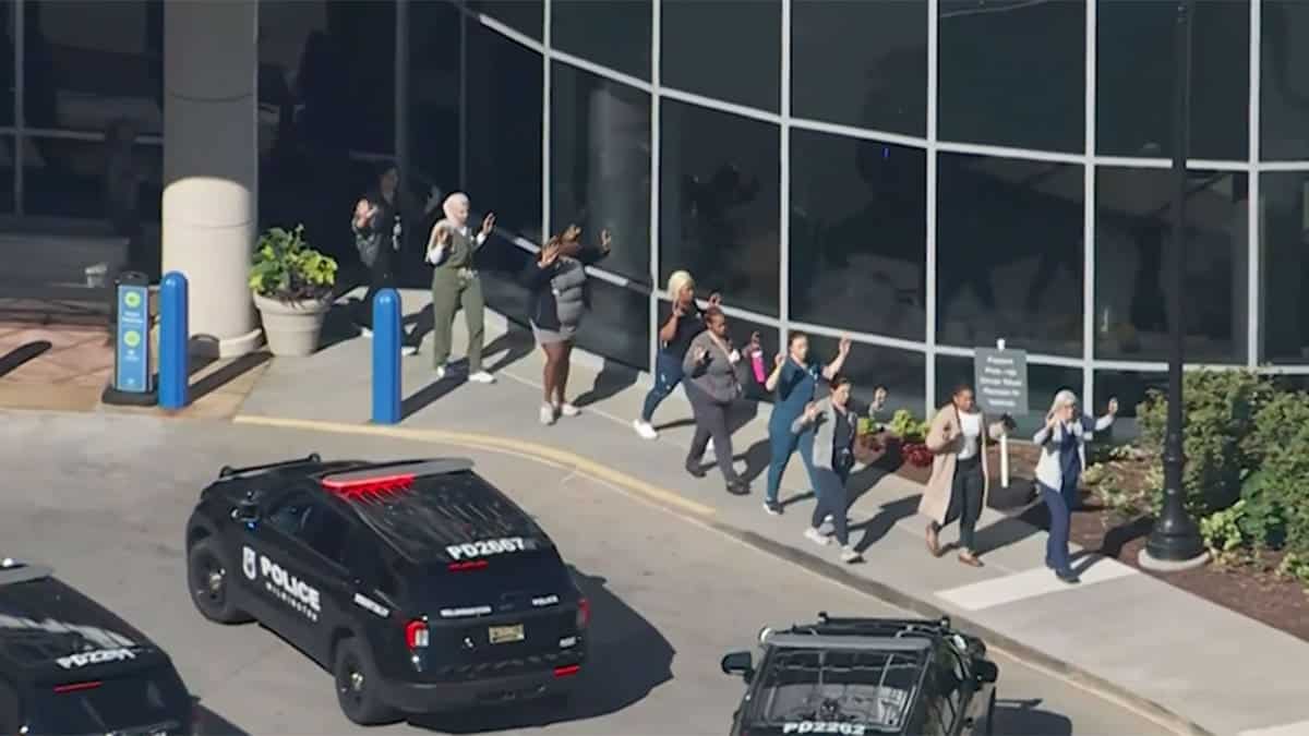 Hospital employees exiting the building with their hands up