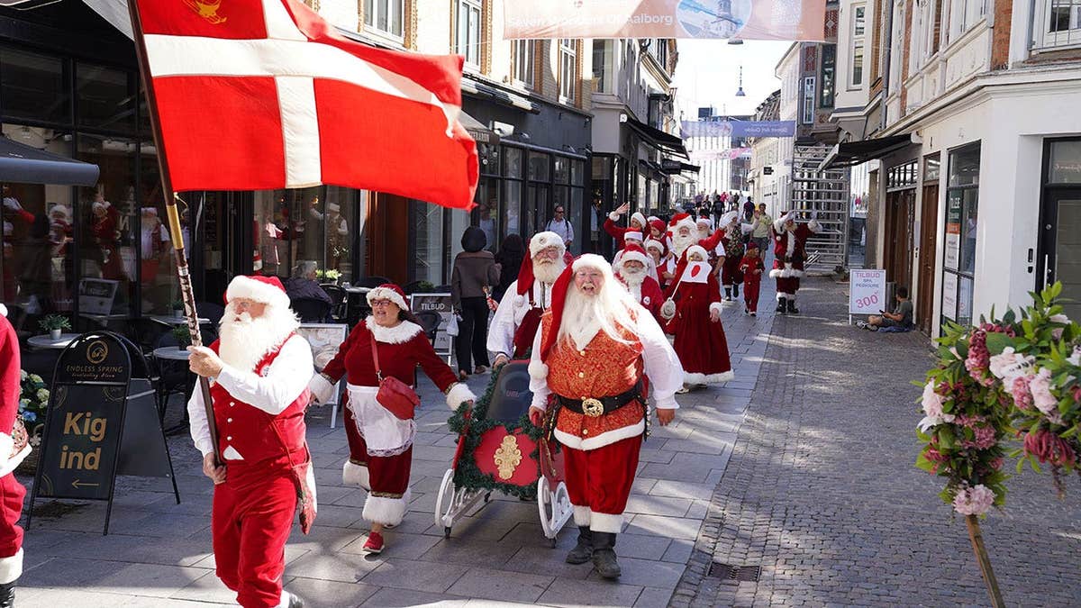 Santas, Mrs. Clauses and Christmas elves march in a parade through a street in Aalborg, Denmark.