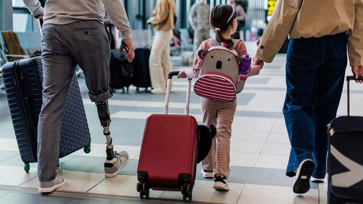 Family walks through airport terminal with luggage.