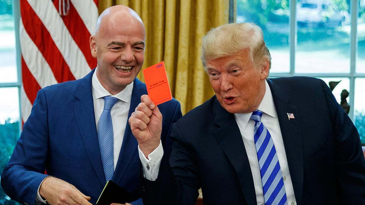 President Donald Trump holds up a red card during a meeting with FIFA president Gianni Infantino in the Oval Office.
