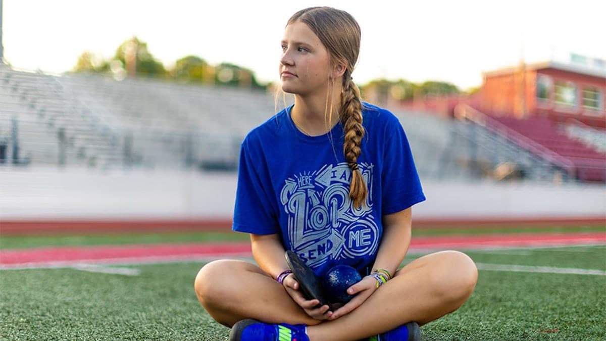 Adaleia Cross sits in the grass
