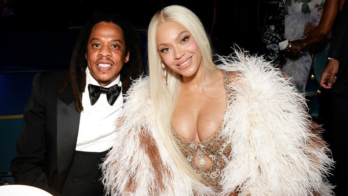 Jay-Z and Beyonce sitting down and smiling at the camera
