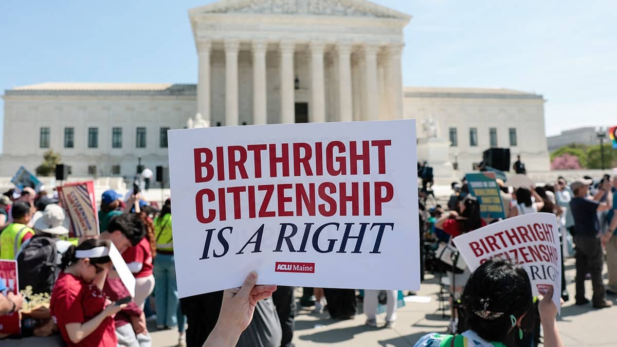 Demonstrators holding signs and rallying on the sidewalk outside the U.S. Supreme Court building.