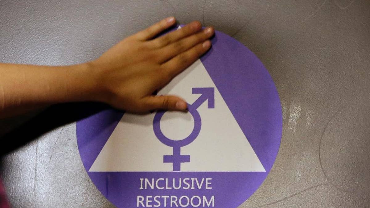 FILE - In this May 17, 2016 file photo, a new sticker is placed on the door at the ceremonial opening of a gender neutral bathroom at Nathan Hale High School in Seattle. Conservatives angered by the inclusion of LGBT protections in an otherwise routine spending bill scuttled the measure Thursday, May 26, 2016, a stark display of the potency of a civil rights issue suddenly prominent in the presidential race and responsible for a legal standoff between the Obama administration and several states. (AP Photo/Elaine Thompson, File)
