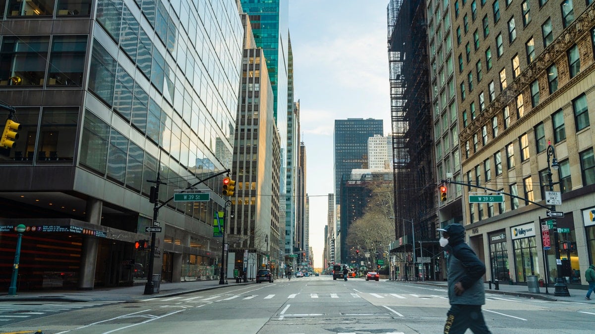 A black man wearing protective mask man crossing 6th Avenue of Americas in Midtown Manhattan deserted because of the city lockdown caused by COVID-19 pandemic.