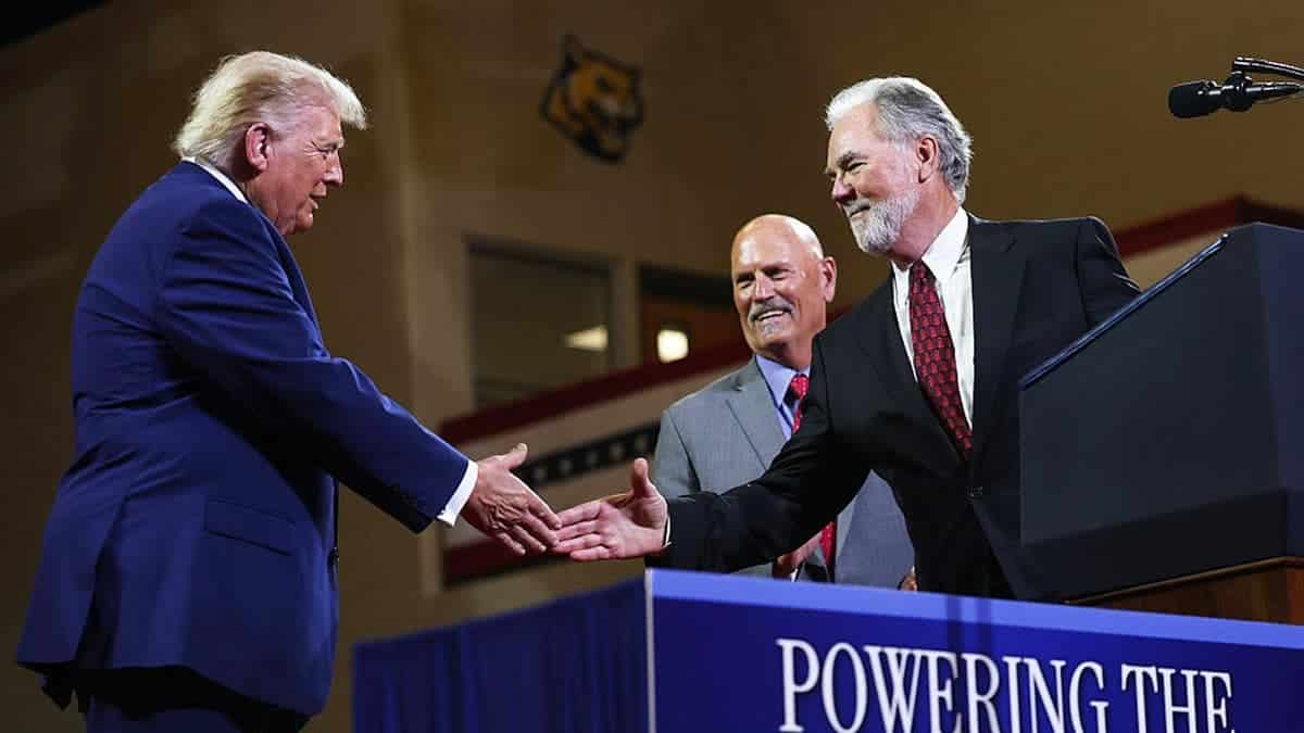 President Donald Trump shakes hands with Mike Plant on stage at Wheeler High School in Marietta, Georgia.