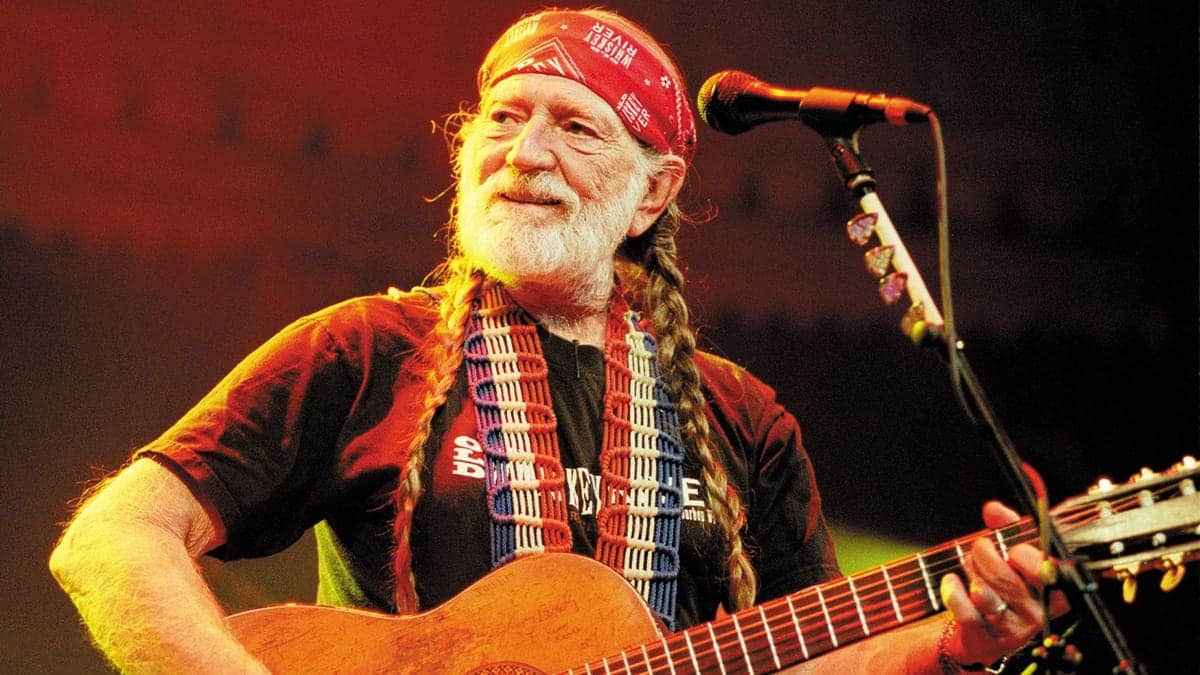 Willie Nelson plays guitar on stage