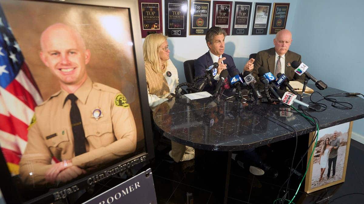 Attorney Bradley Gage, middle, and Kim Clinkunbroomer, left, and Mike Clinkunbroomer, the parents of late Los Angeles Sheriff's Deputy Ryan Clinkunbroomer, pictured left, announce the precursor of a lawsuit against the Sheriff's Department at a news conference in Los Angeles on Tuesday, Nov. 28, 2023. Los Angeles County Sheriff's Deputy Clinkunbroomer was shot and killed Sept. 16, 2023, while sitting in his patrol car in Palmdale, Calif. His parents are seeking justice for their son and looking to make a change in LACSD's policies to protect other deputies from death.