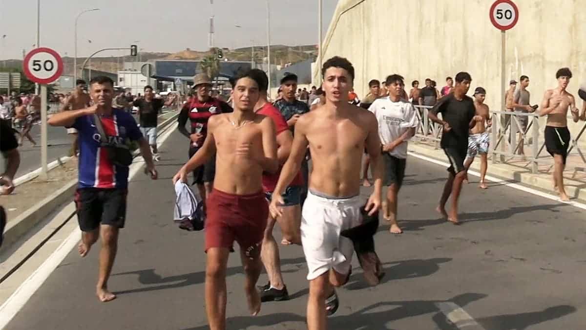 Migrants run and cheer as they cross on foot into the North African enclave of Ceuta from Morocco, after swimming over from the Moroccan side and overwhelming police at the city's breakwater, according to Spain's Guardia Civil, in Ceuta, Spain, July 30, 2026.