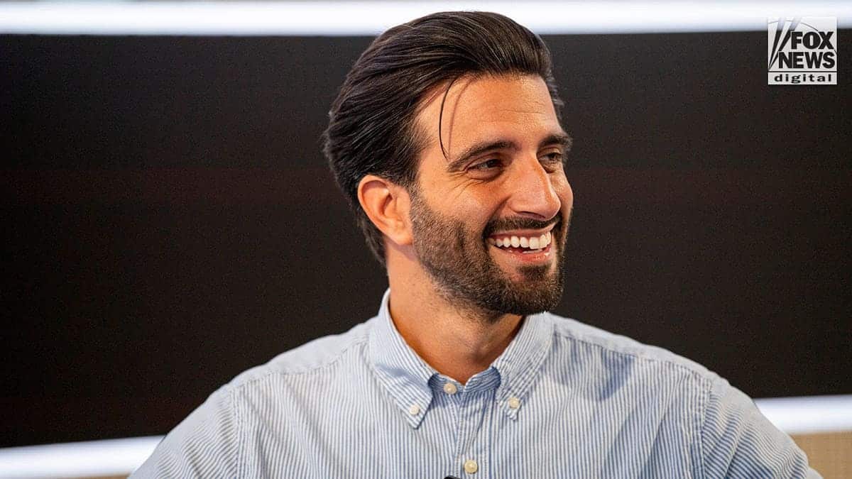 Davide De Pierro grins in a blue and white striped shirt.